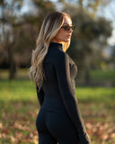 Woman in a black outfit walking outdoors with trees in the background