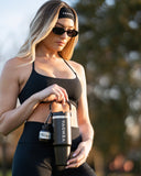 Woman holding a black VENOVA shaker bottle outdoors