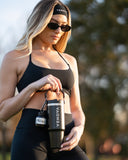 Woman holding a black VENOVA shaker bottle outdoors