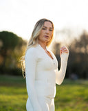 Woman in a white outfit standing in a field with a blurred background