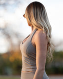 Woman wearing a beige athletic outfit with a blurred natural background