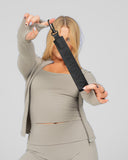 Person holding a black strap against a plain background