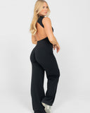 Woman wearing a black open-back jumpsuit on a white background