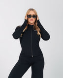Woman wearing a black tracksuit and sunglasses on a white background