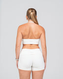 Person wearing a white bandeau top and shorts on a gray background