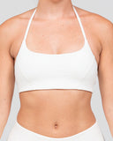 Person wearing a white sports bra against a plain background