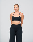 Woman wearing a black sports bra and leggings on a gray background