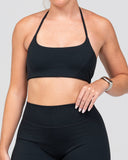 Person wearing a black sports bra and leggings on a light gray background