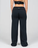 Person wearing black wide-leg pants with a visible brand logo Venova on a plain background