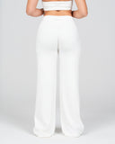 Person wearing a white strapless top and wide-leg pants on a light gray background